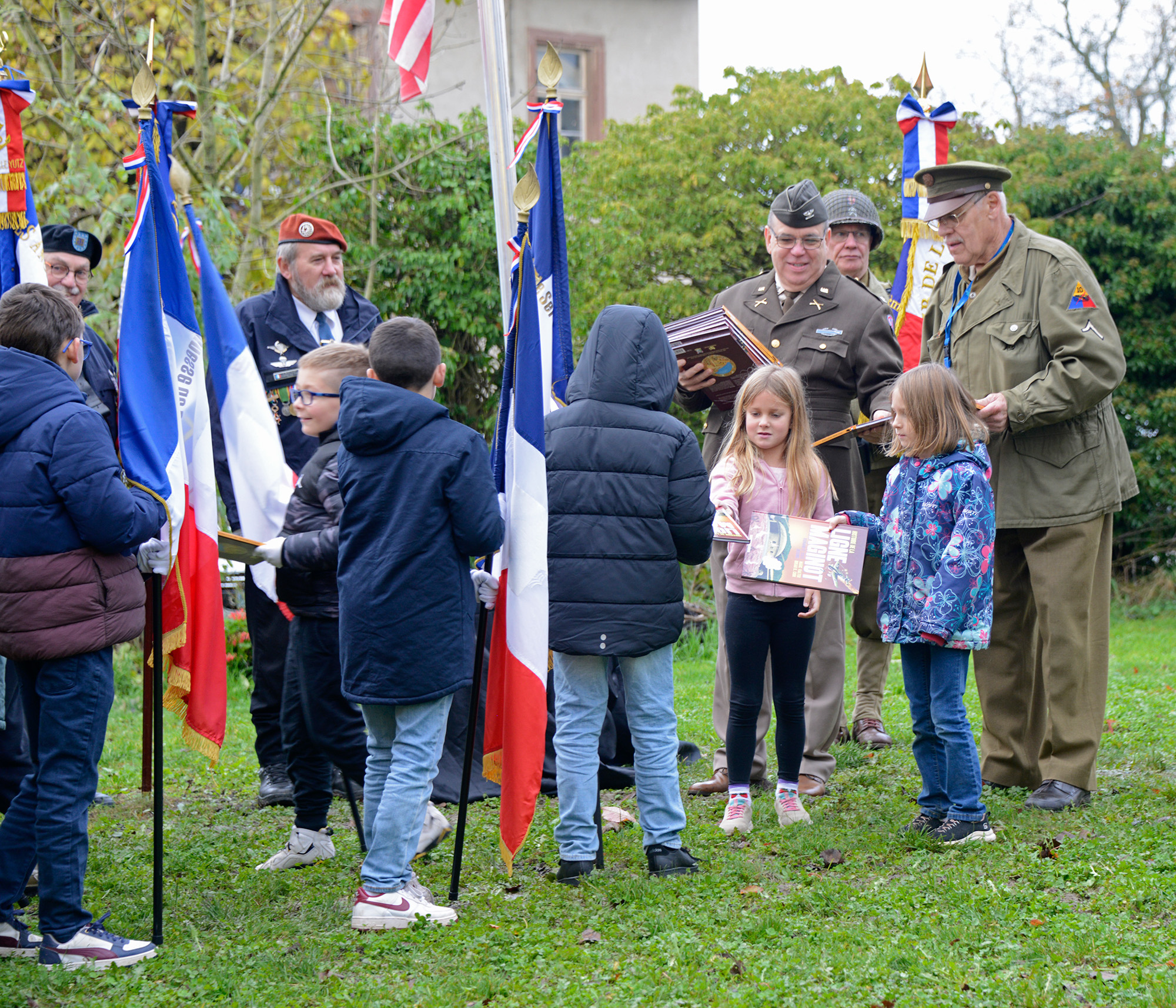 Two young decendants of Joseph Stebbe help Pascal Moretti and Jacques Eberlé distribute copies of Historie de la Ligne Maginot to local children participating in the commemorations.