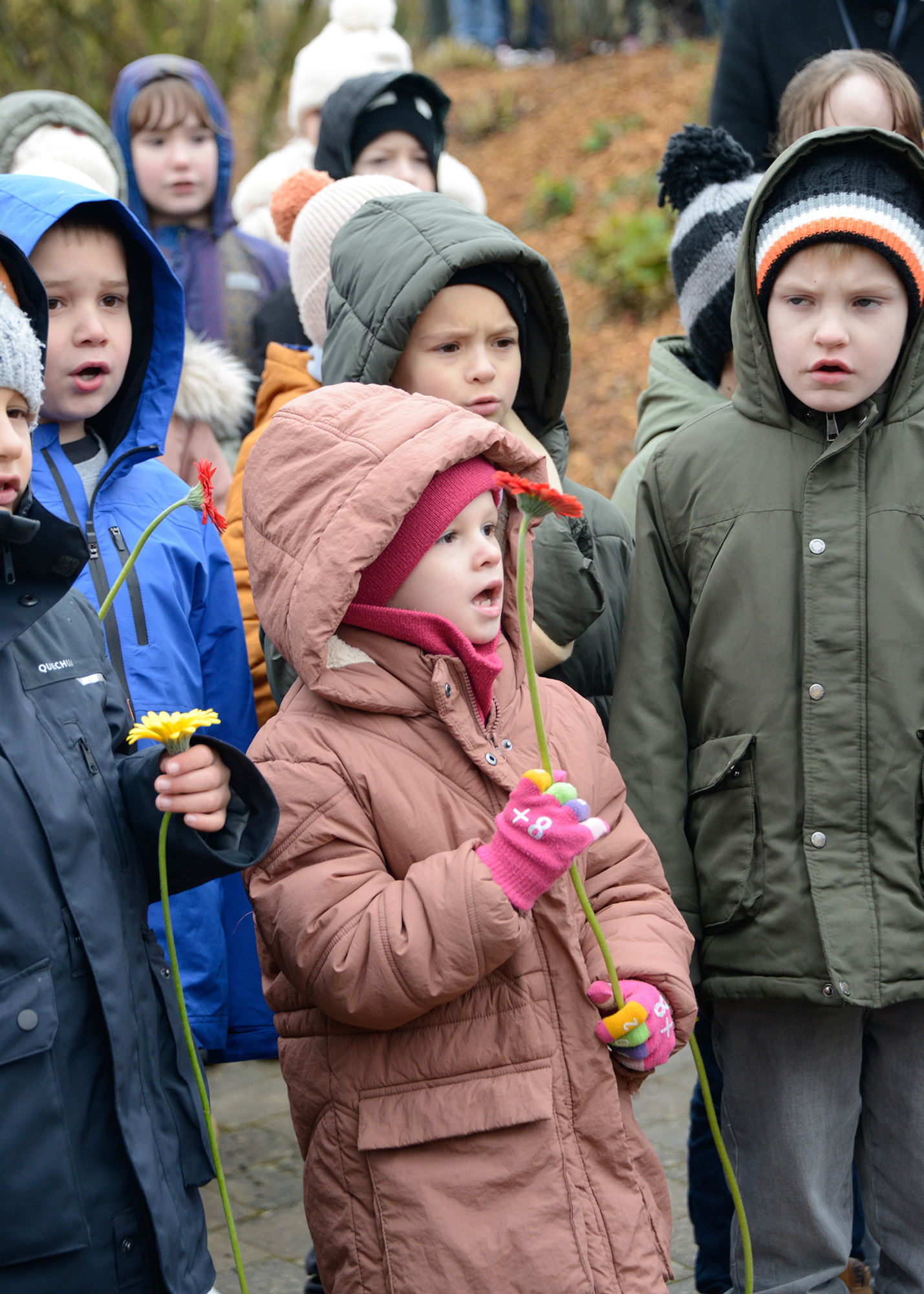 Local school children sing and place flowers at the monument dedicated to Staff Sergeant Walter O. Brunko.