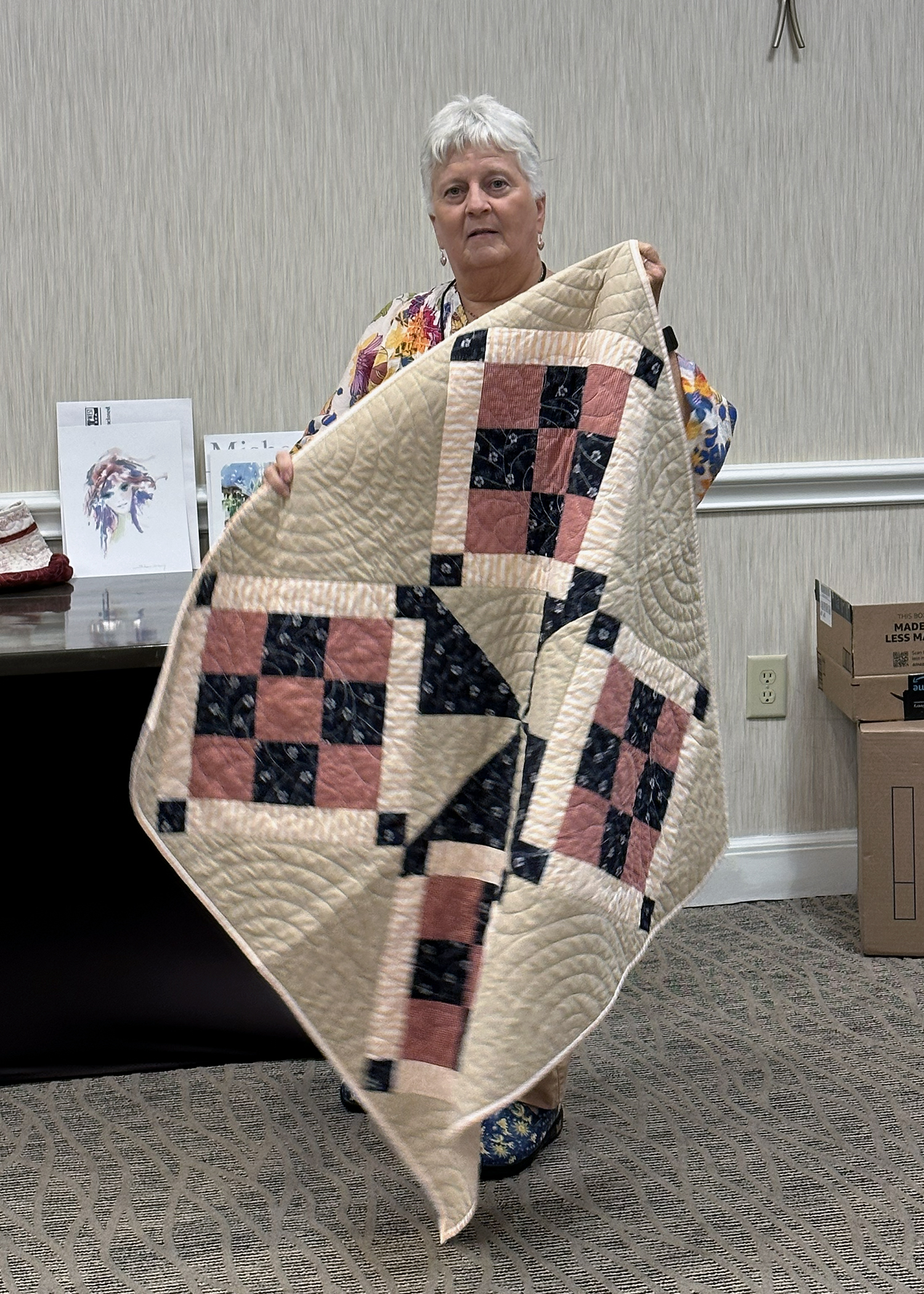 Billie Bauer proudly displays the handmade quilt she won in the Victory Belle raffle.