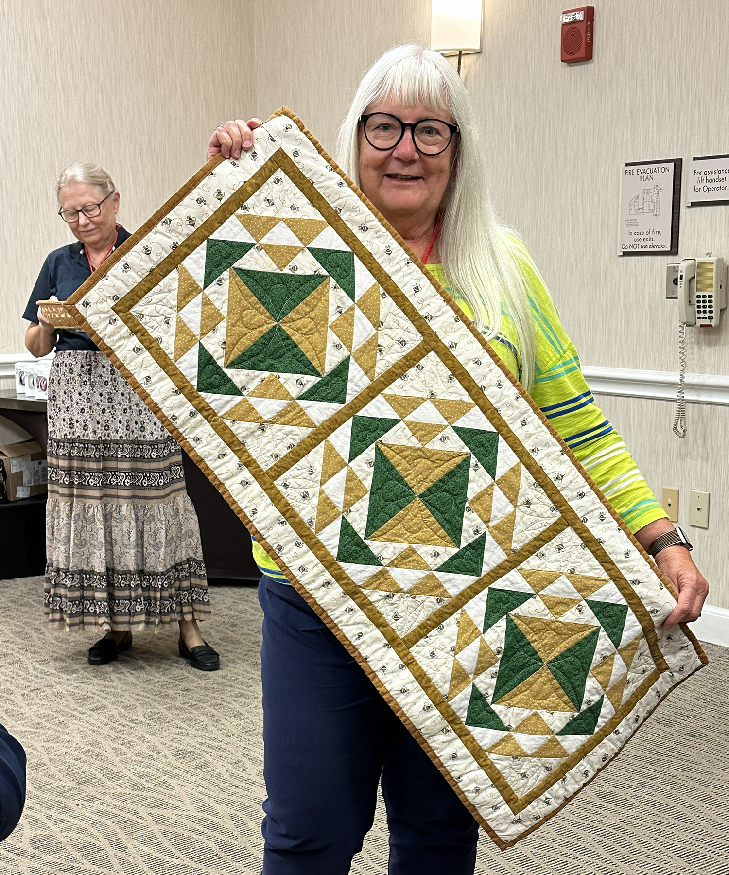 Marsha Flora is delighted to win a bee quilt table runner made by Kim Kowalczyk for the Victory Belle raffle.