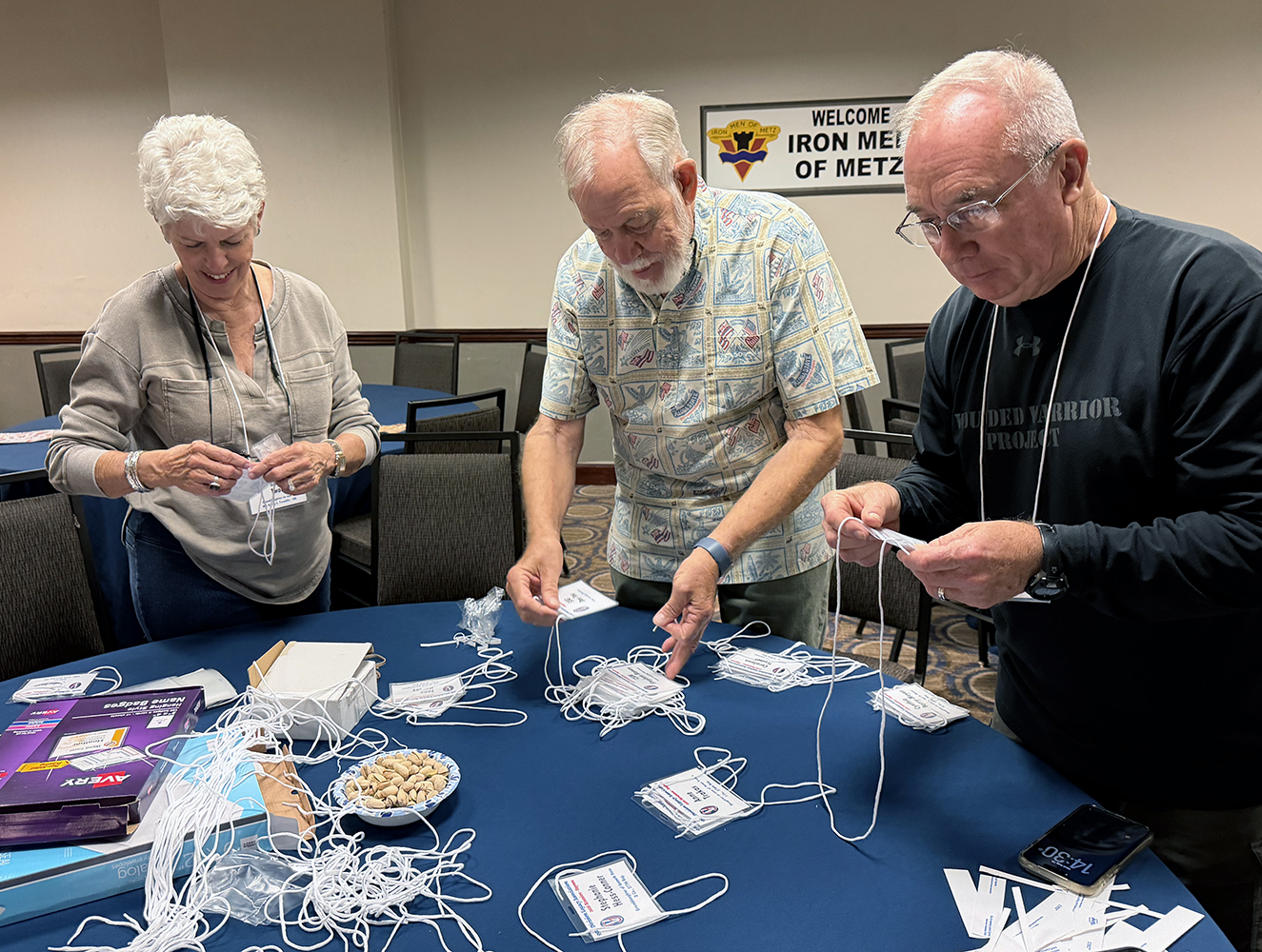 In the Hospitality Room of the Doubletree by Hilton, Kathy Twaddle, David Meyer and Dan Foust help assemble name badges for the reunion.