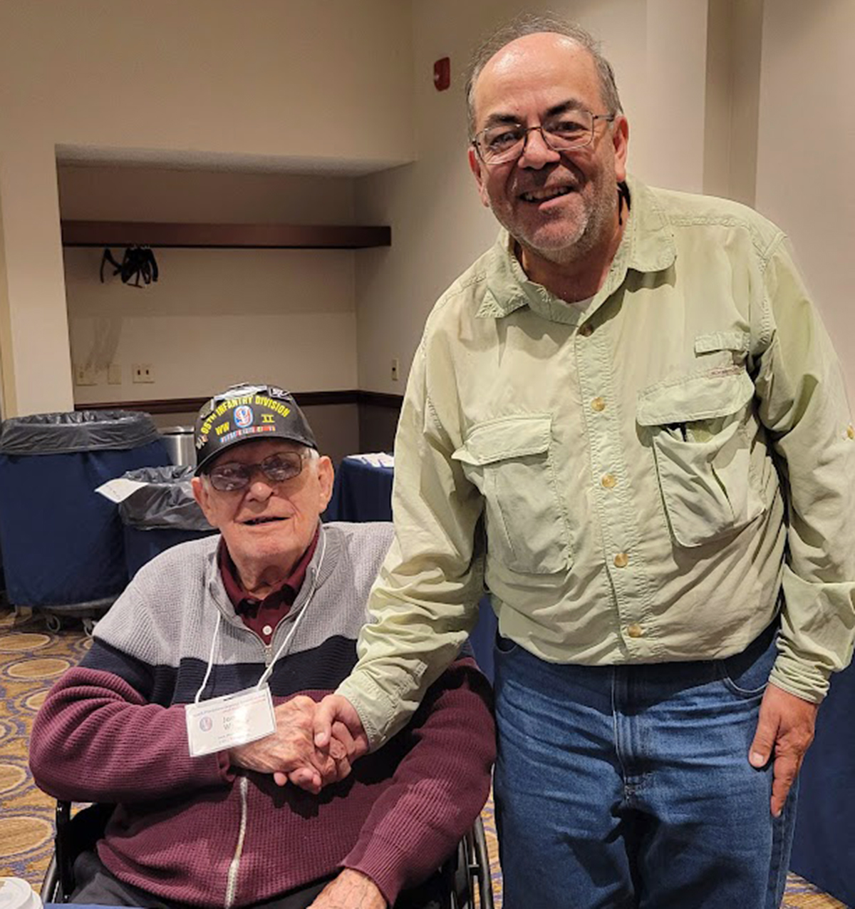 Iron Man Jim Walker meets first-time reunion attendee Ron Heisterkamp in the Hospitality Room.